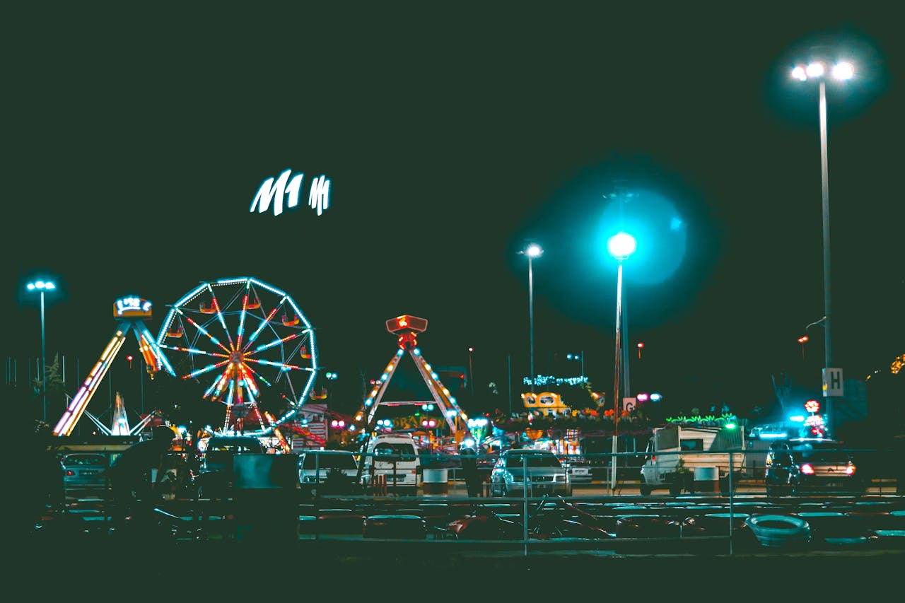 Vibrant nighttime scene of an illuminated amusement park with a ferris wheel and rides.